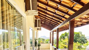 A covered balcony with a view of greenery and mountains. - Pousada Preciosa (Búzios)