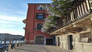 A stone-paved walkway leading to a red building with a balcony.