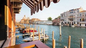 A canal view with boats docked, historic buildings, and a wooden pier.