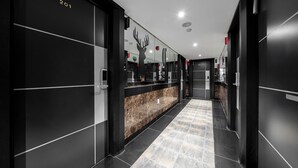 A modern hotel corridor with black walls, numbered doors, a marble counter, and a tiled floor. - shincheon noble stay hotel (Seoul)