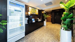 A hotel reception area with a refrigerated display, a coffee machine, and a potted plant. - shincheon noble stay hotel (Seoul)