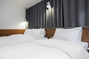 A hotel room with a large bed, wooden headboard, and a curtain-covered window. - shincheon noble stay hotel (Seoul)