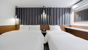 A hotel room with a large bed, a bedside table, a lamp, and an air conditioning unit. - shincheon noble stay hotel (Seoul)