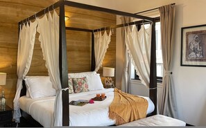 A four-poster canopy bed with white linens, a floral pillow, and a tray with two drinks. - Villa One - Pvt Pool Outdoor Deck North Goa (Nerul)