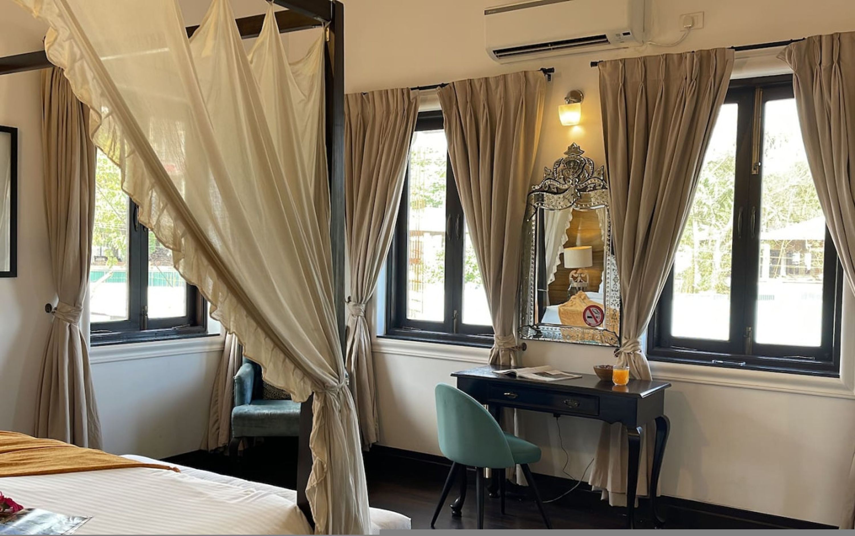 Une chambre d’hôtel avec un lit, un bureau, une chaise et une grande fenêtre avec des rideaux.