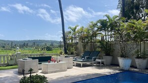 A poolside area with lounge chairs, a table, and potted plants. - Villa One - Pvt Pool Outdoor Deck North Goa (Nerul)