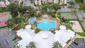 An aerial view of a hotel with a central swimming pool, tennis courts, and a landscaped courtyard. - 4 Bed In Windsor Palms Resort - Steps To Disney 4 Bedroom Villa by RedAwning (Kissimmee)