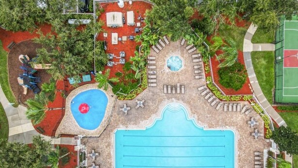 An aerial view of a resort with a large central pool, smaller circular pool, and various seating areas surrounded by palm trees and greenery. - 4 Bed In Windsor Palms Resort - Steps To Disney 4 Bedroom Villa by RedAwning (Kissimmee)