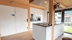 Una cucina moderna con mobili bianchi, un'isola centrale e un soffitto in legno.