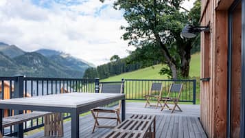 Enjoy a serene view from this outdoor space with a table and two chairs, overlooking the surrounding mountains and a tree.