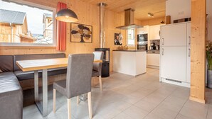 Une cuisine moderne avec des meubles en bois, un îlot central et un coin repas comprenant une table et des chaises.