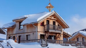 Un chalet en bois doté d’un balcon, entouré de neige.