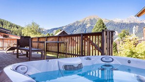 Ein Whirlpool auf einer Holzterrasse mit Blick auf die Berge.