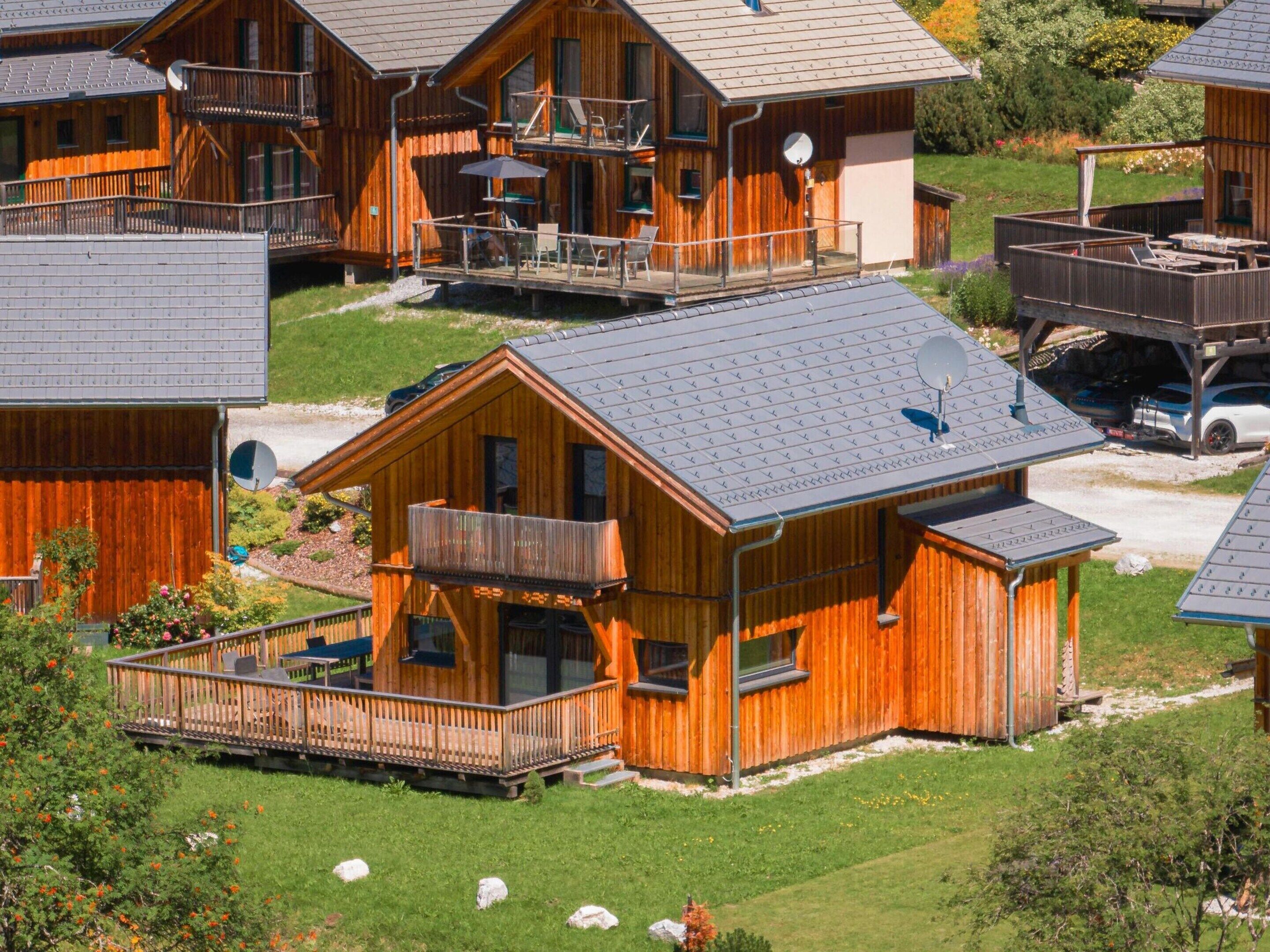 Une cabane en bois dotée d’un balcon, d’un espace extérieur couvert aménagé en coin salon et d’une antenne parabolique.