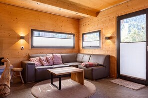 L’intérieur d’un chalet chaleureux, avec un canapé, une table basse et une sculpture en bois.