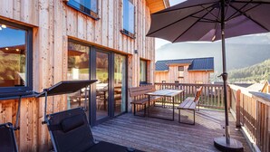 Une cabane en bois dotée d’une terrasse, de meubles de jardin et d’un grand parasol.
