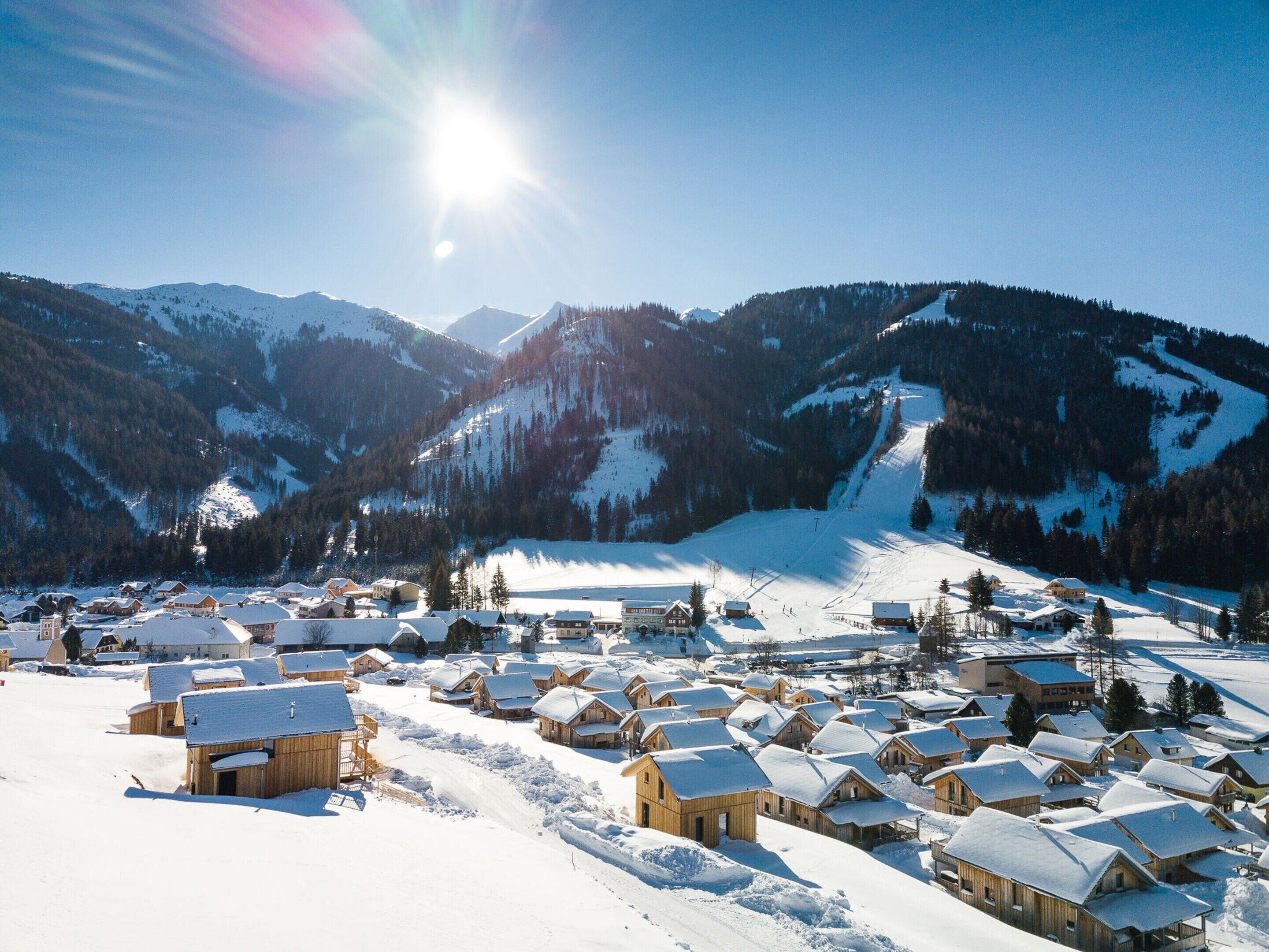 Un villaggio innevato con case di legno e una pista da sci.