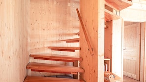 A wooden staircase with multiple steps leading upwards, surrounded by wooden walls and a wooden door in the background. - Chalet in Hohentauern Near Ski Slopes (Hohentauern)