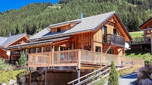 A wooden chalet with a balcony, a stone foundation, and a mountain backdrop. - Chalet in Hohentauern Near Ski Slopes (Hohentauern)