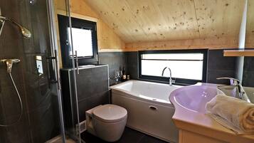 Un baño moderno con ducha envuelta en vidrio, una bañera y un lavamanos.