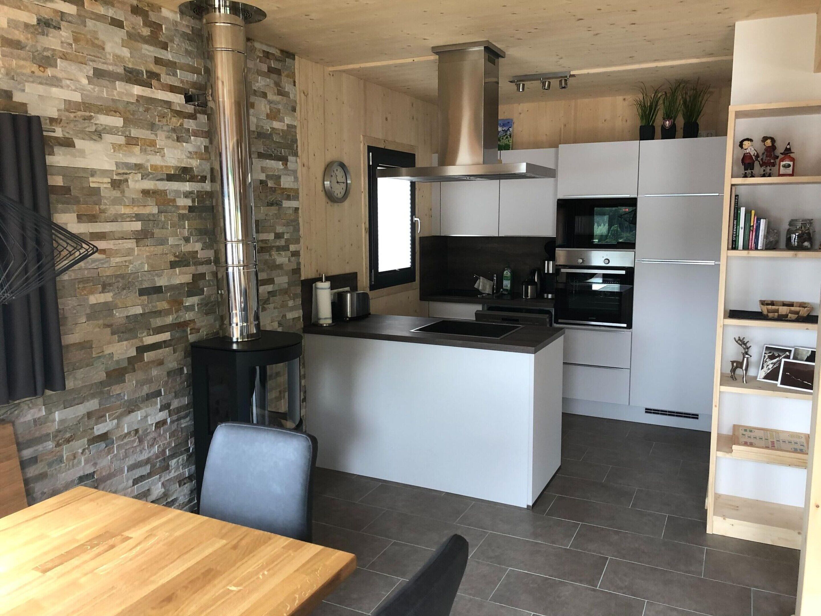 Eine moderne Küche mit einer zentralen Kochinsel, Edelstahlgeräten und einer Wand mit Steinverkleidung.
