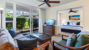 A hotel room with a balcony, a television, a bed, and a dining area with a table and chairs.