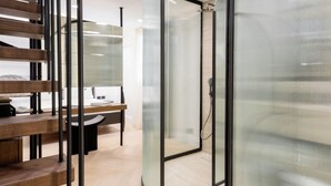 A modern office space with a wooden staircase, a glass-walled meeting room, and a visible shower area. - Emerald Hotel Athens (Athens)