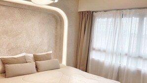 A modern bedroom with a large bed, a unique ceiling light fixture, and sheer curtains. - UDMS On nut 10 (Bangkok)