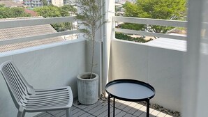 A balcony with a potted plant, a white chair, and a small round table. - UDMS On nut 10 (Bangkok)