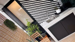 A modern outdoor area with a bamboo floor, a wooden bench, and potted plants. - UDMS On nut 10 (Bangkok)