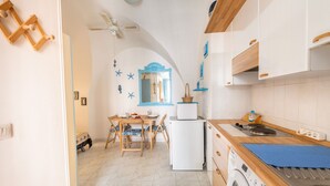 Una cucina funzionale con lavatrice, un'area pranzo con tavolo e sedie, e una ventola a soffitto.