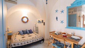 Una camera da letto con un letto, un comodino e un'area pranzo con tavolo e sedie.