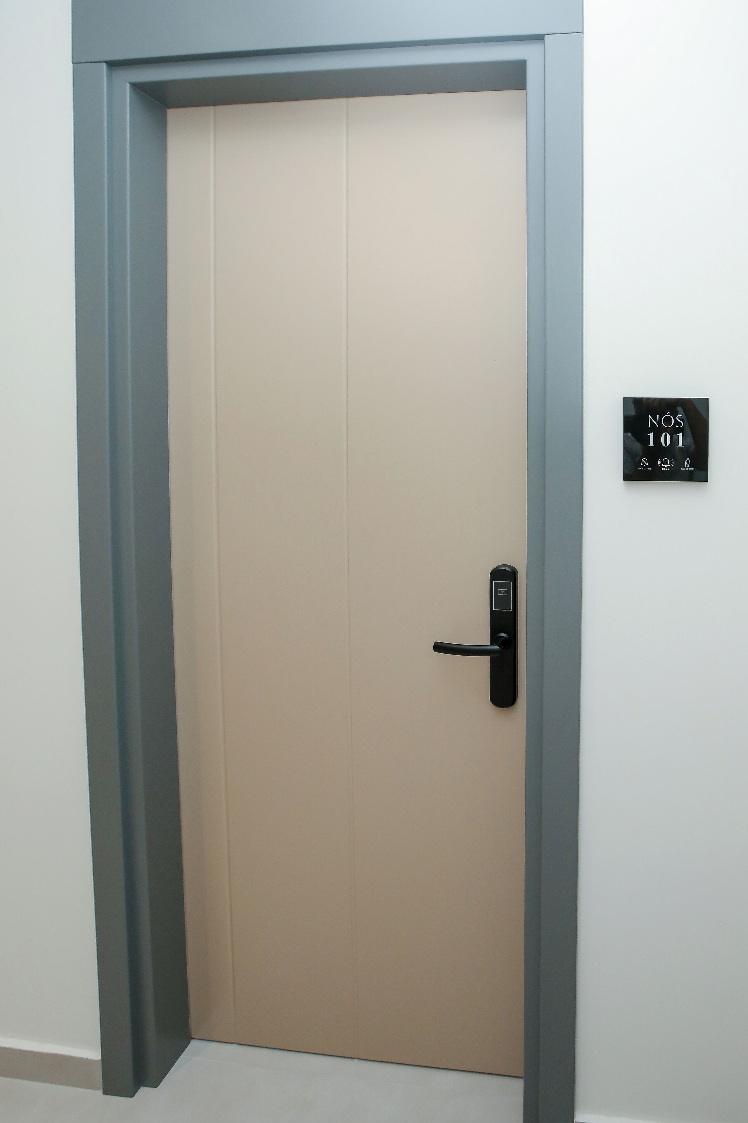 Puerta cerrada con un moderno teclado electrónico y un cartel que indica el número de habitación 101.
