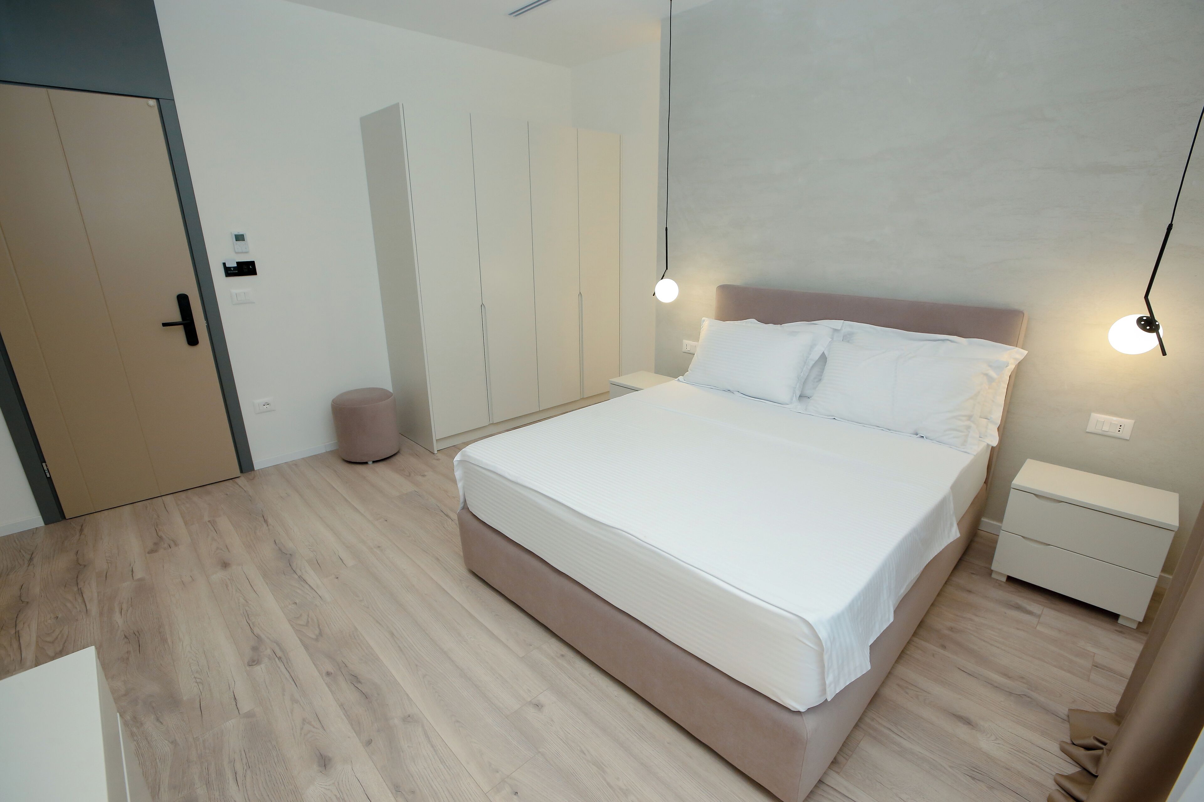 Een moderne slaapkamer met een groot bed, nachtkastjes en een kledingkast.