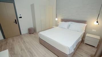 Een moderne slaapkamer met een groot bed, nachtkastjes en een kledingkast.