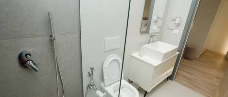 Un bagno moderno con cabina doccia in vetro, un water e un lavandino.