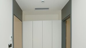 Un couloir avec une armoire blanche, une porte dotée d’une poignée et un interrupteur sur le mur.