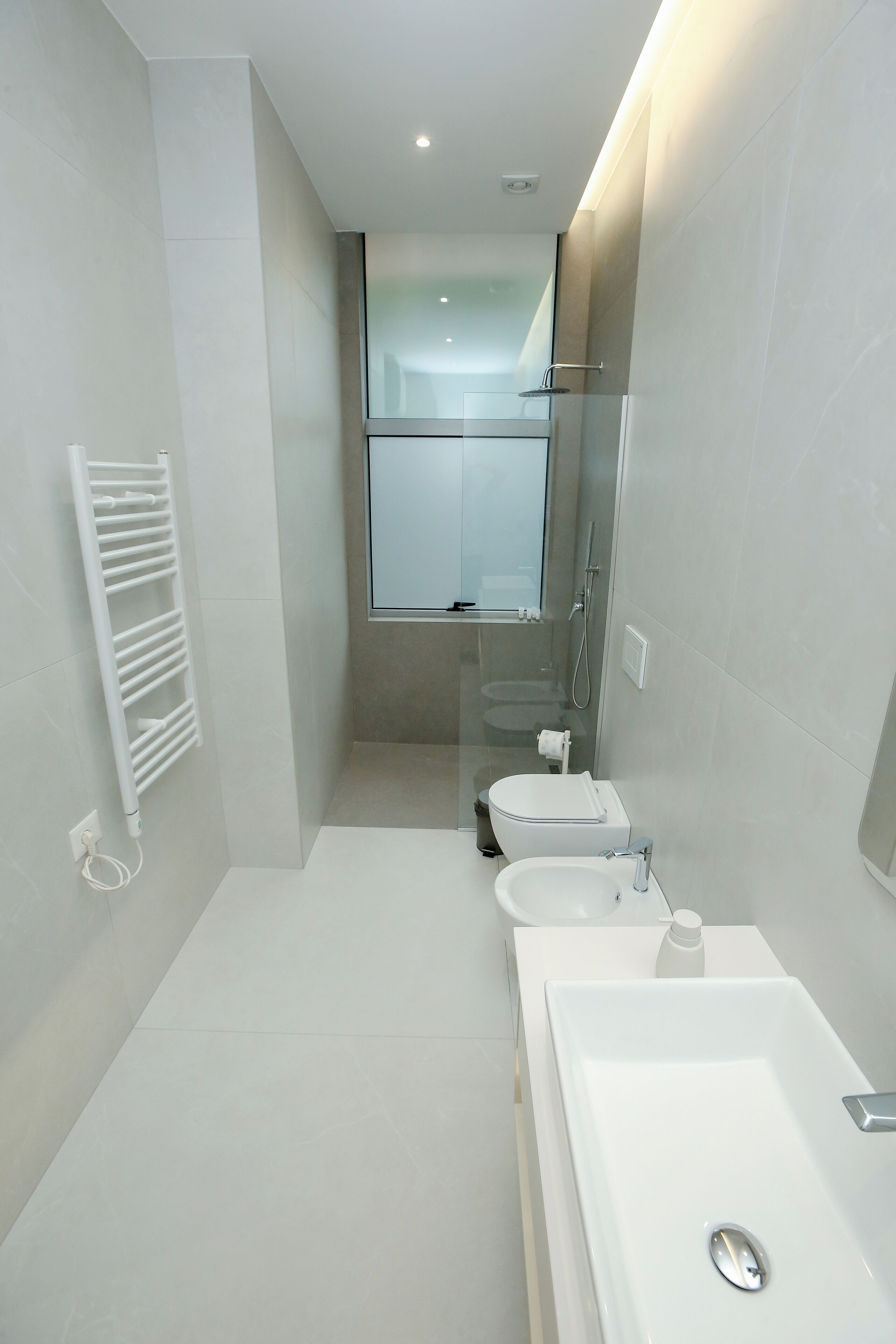 A modern bathroom with a walk-in shower, a toilet, and a large sink.