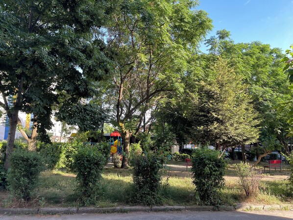 Un parque con árboles, un área de juegos y un banco.