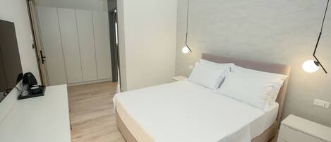 A bedroom with a bed, bedside tables, a wardrobe, and a coffee machine.