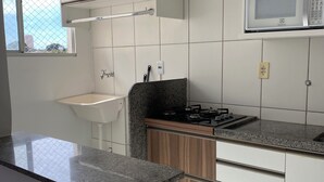 A modern kitchen with white cabinets, a granite countertop, a microwave, and a gas stove.