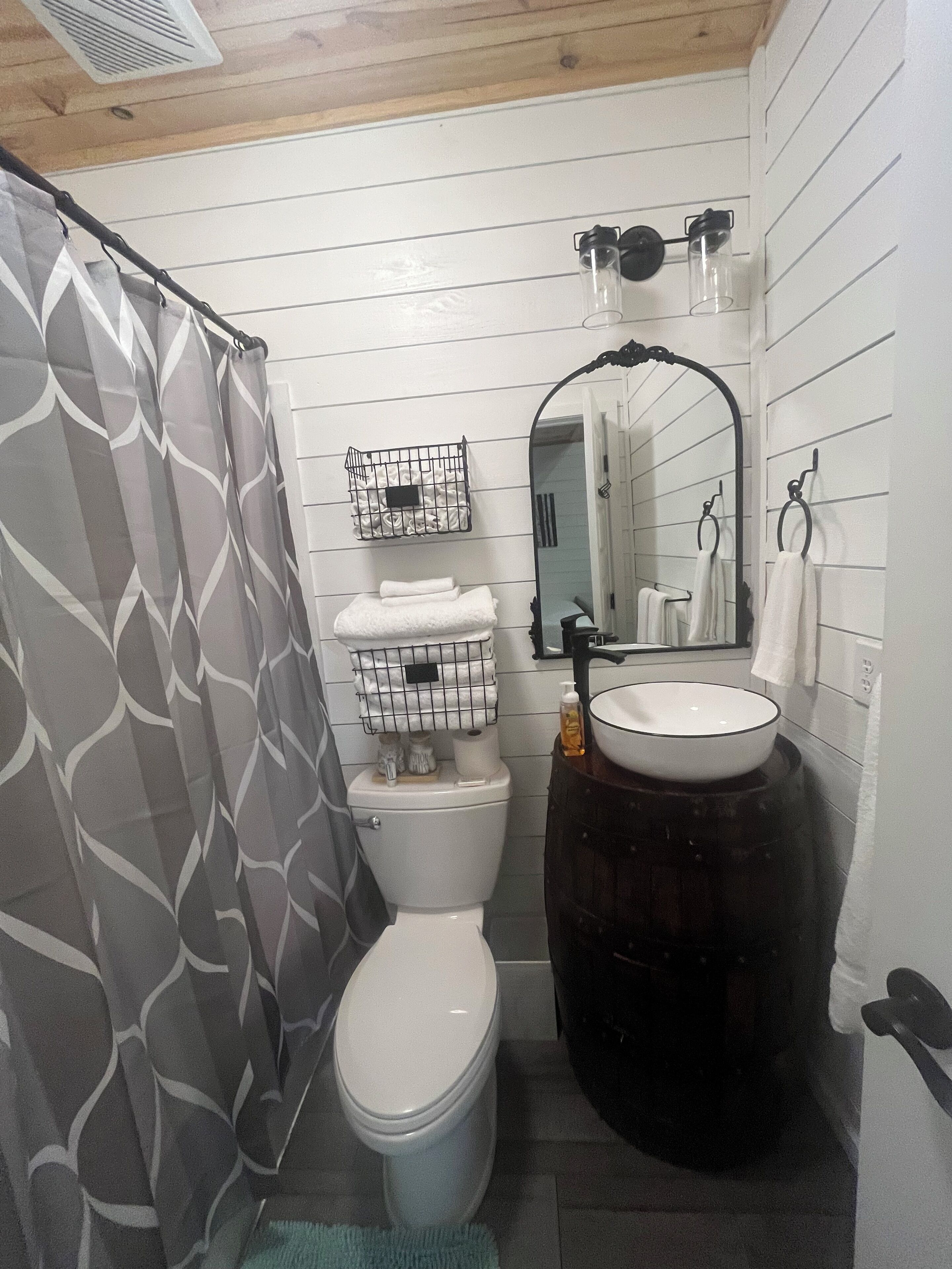 Une salle de bain comprenant des toilettes, un lavabo, un grand miroir et un rideau de douche.