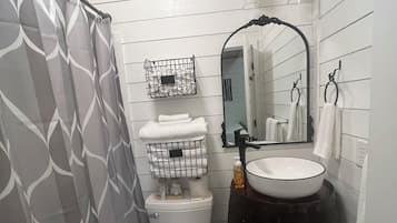 Une salle de bain comprenant des toilettes, un lavabo, un grand miroir et un rideau de douche.