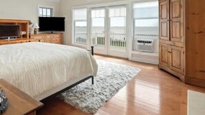 A bedroom with a bed, a TV, a wooden cabinet, and a large window. - Views ! Views! Views ! Water Front Property 
4 bedroom house  in Southampton  (Southampton)