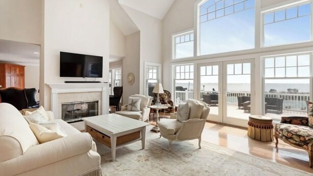 A spacious living room with a fireplace, a television, and large windows offering a view of the outdoors. - Views ! Views! Views ! Water Front Property 
4 bedroom house  in Southampton  (Southampton)