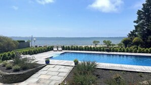 A rectangular swimming pool with a view of the sea, surrounded by a stone deck and greenery. - Views ! Views! Views ! Water Front Property 
4 bedroom house  in Southampton  (Southampton)
