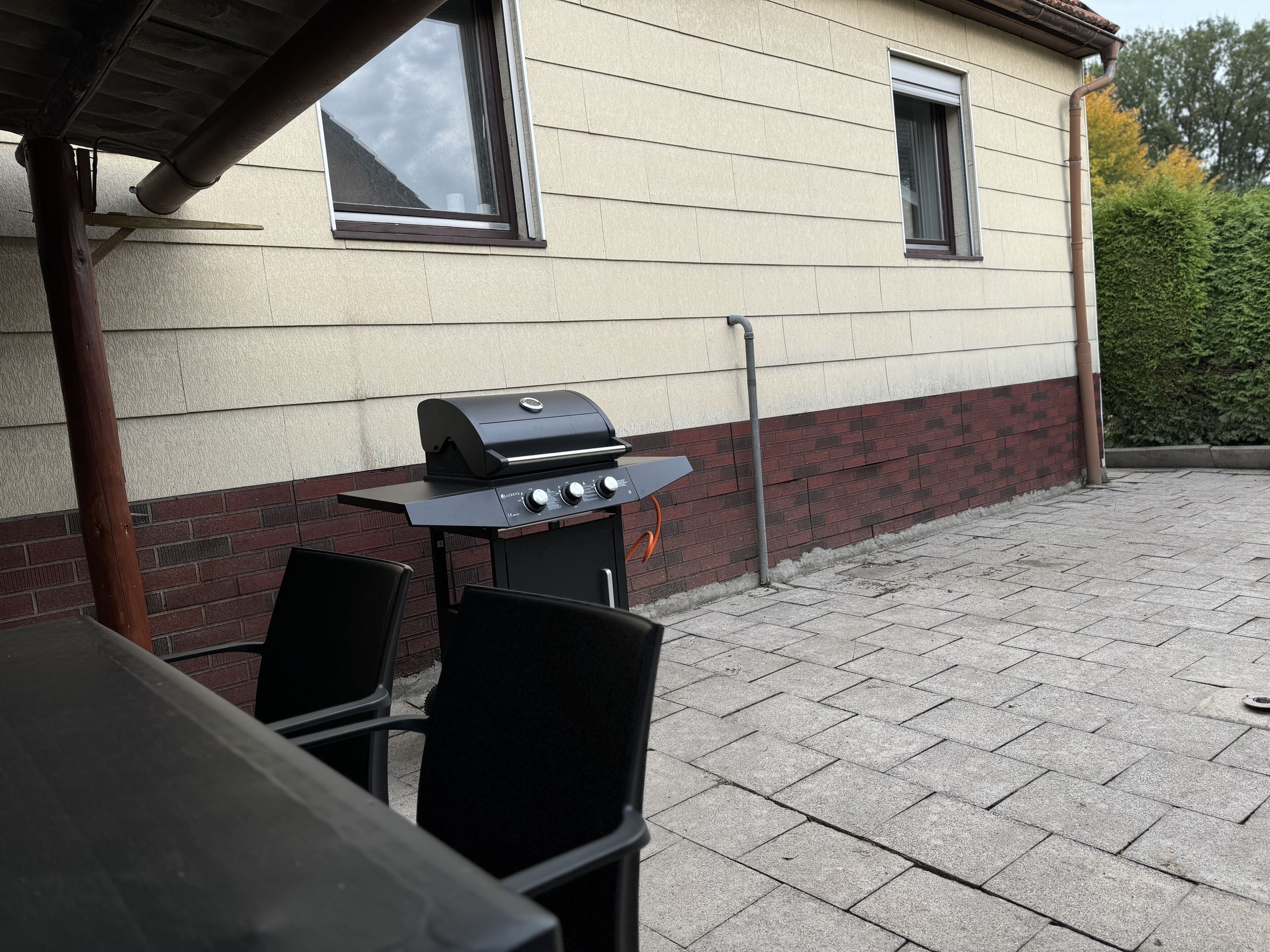 An outdoor patio with a grill, chairs, and a table.
