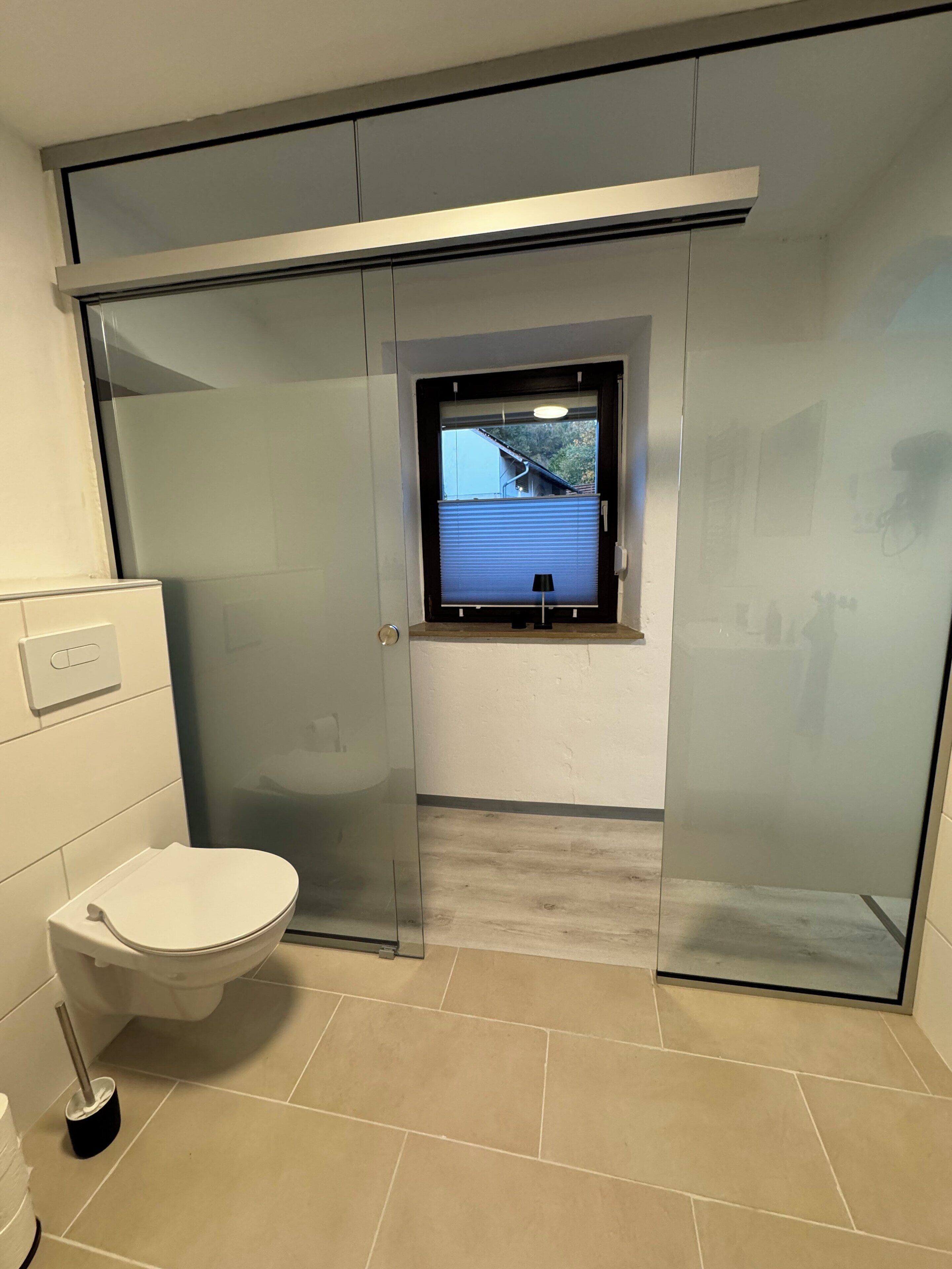 A modern bathroom with a toilet, a bidet, and a window.