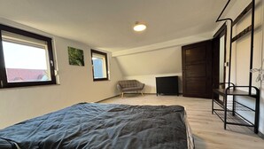 Een slaapkamer met een bed, een stoel, een kaptafel en een stapelbed.