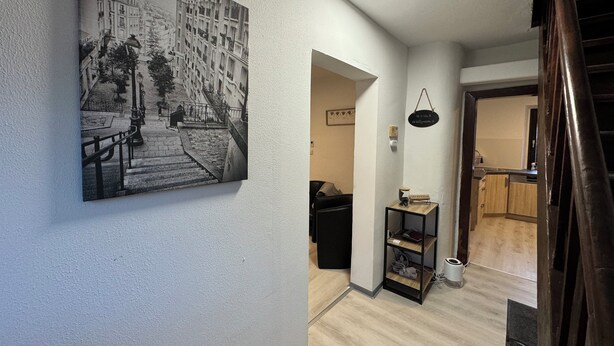 Een gang met een zwart-witfoto van een straat, een klein tafeltje met een lamp en een hangend bord.